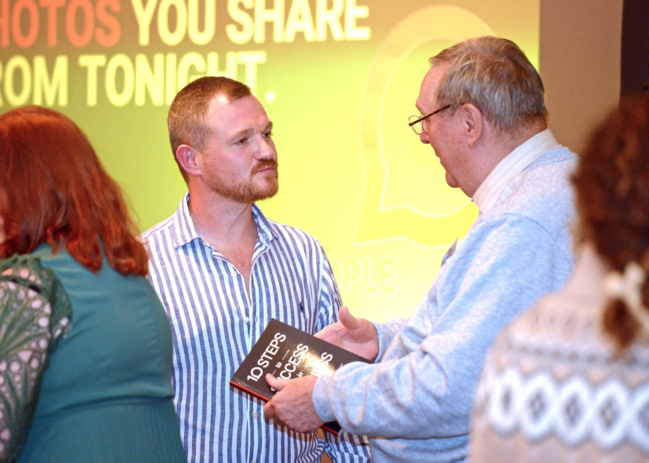 Sean O'Neill deep in conversation with an audience member at the MSO Finding the Right People event, with the audience member holding a copy of Sean's book 10 Steps to Success in Business